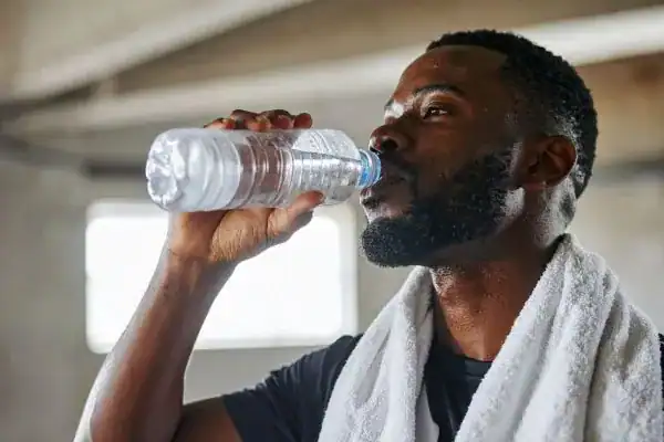 Image of man drinking water to improve hydration Horsham after work out.